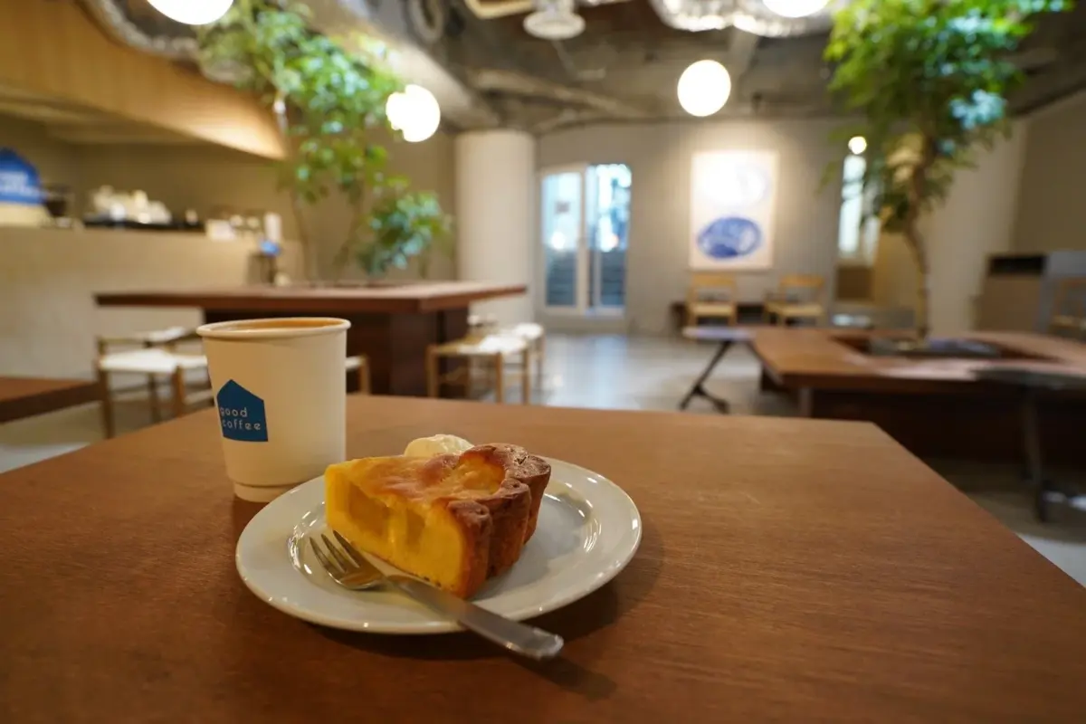 モダンなカフェで、木製のテーブルに置かれたコーヒーカップとケーキ