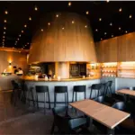 Modern cafe interior with a curved wooden bar black stools and warm pendant lighting overhead