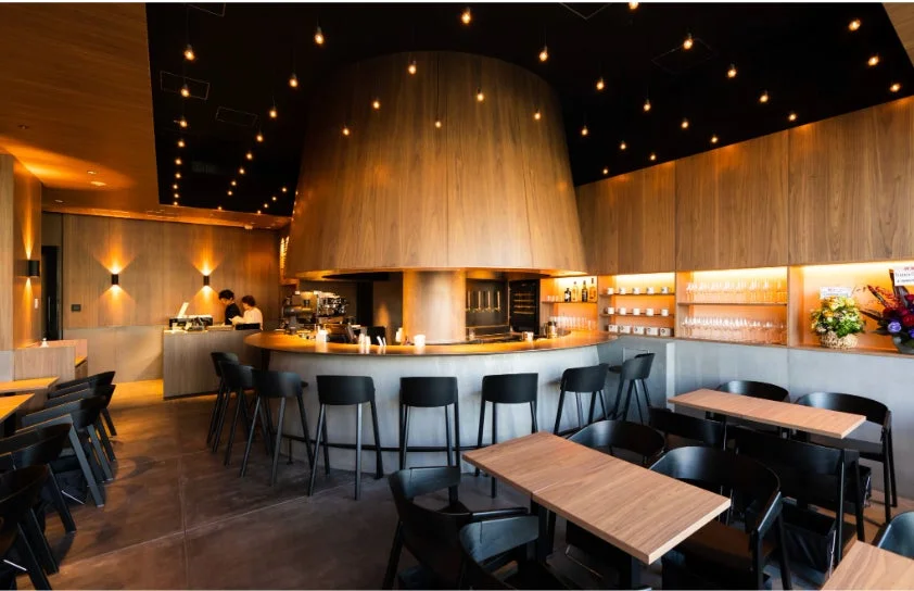 Modern cafe interior with a curved wooden bar black stools and warm pendant lighting overhead
