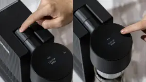 Hands press levers on a black coffee machine circular dial reads CUSTOM BREW