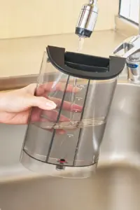 Clear water reservoir being filled under a kitchen faucet with measurement marks visible on its side 46