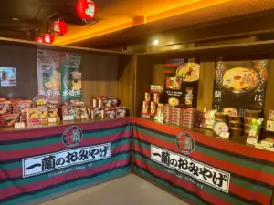 Display of Japanese ramen products and packaging on a storefront counter with colorful striped banners reading Original Goods One Ran and Japanese text