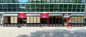 Caffè Veloce storefront with red awnings and large glass windows in a modern building facade