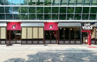 Caffè Veloce storefront with red awnings and large glass windows in a modern building facade