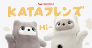 8187f53324f5235cc40a3172ef9f0ebd | コーヒーステーション Two soft cat like plush robots from SwitchBot KATA Friends wave hello with large orange KATAフレンズ text in the background