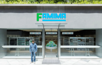Front of a FAMIMA convenience store with a green and blue sign a person in denim stands outside the glass storefront