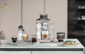 Espresso machine on a kitchen counter with several coffee drinks a grinder and a plate of toast on the right side