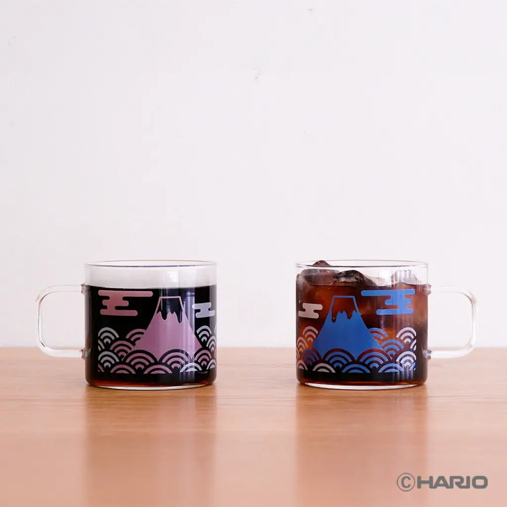 Two clear glass mugs filled with dark beverages on a wooden table purple and blue Mount Fujiwave designs with a HARIO watermark