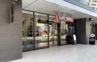 Exterior view of a café storefront named Caffè Veloce with glass doors and a sidewalk chalkboardmenu board outside