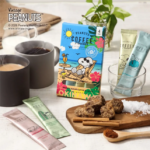 Peanuts Coffee Powder packaging with Snoopy artwork two mugs of coffee and sachets on a light table with a wooden board holding brown sugar chunks and a cinnamon spoon