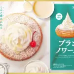 Cake with whipped cream and a cherry on a dusted round base next to a teal promotional panel for Blanc Noire pastry seasonal