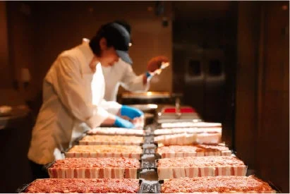 厨房で料理人がミートローフのような肉料理を準備している様子