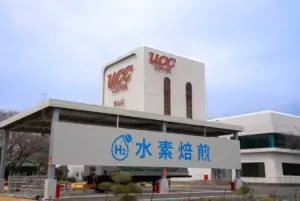 Exterior view of a white building with UCC Coffee signage and a large banner displaying an H2 symbol and blue Chinese text