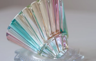 Iridescent glass sculpture shaped like a wide fan with rainbow-colored ridges, resting on a clear base.