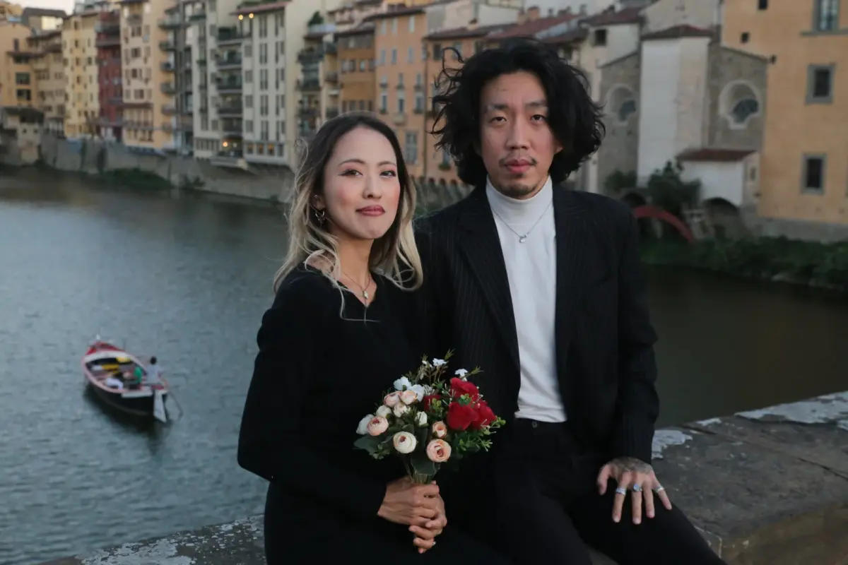 歴史的な建物と川を背景に花束を持ったアジア人カップル