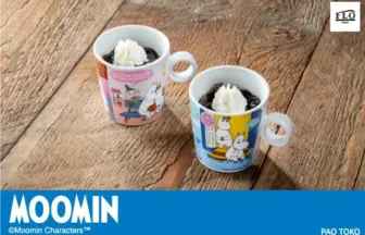 Two Moomin themed mugs with whipped cream topped desserts on a wooden table