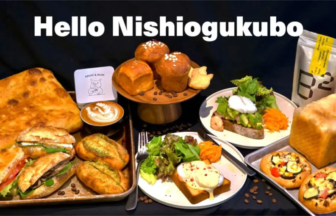 Bakerycafé spread featuring a large loaf sandwiches croissants savory pastries pizzas and a latte on a dark table beneath Hello Nishiogukubo text showcasing a cafe menu
