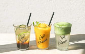 Three iced drinks in clear glasses on a wooden table cucumber tea left mango smoothie center and matcha latte right