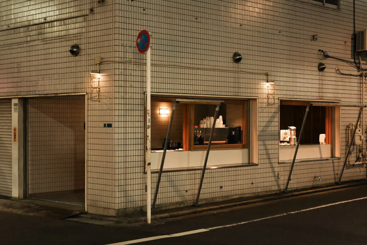 夜の街角に佇むタイル張りの建物、カフェのような店内