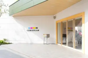 Modern white building entrance with a colorful bar logo above the doorway and the word GENIUSLAB on the wall