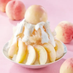 Peach dessert in a bowl with whipped cream surrounded by peach slices on a pink surface