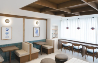 Bright cafe interior with booth seating along a teal tiled wall and a long bar counter with wooden stools by a large window with sheer curtains
