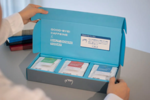 Bright blue box opened to reveal three coffee sachets labeled Fine Light Rich Medium and Deep Dark inside a home setting
