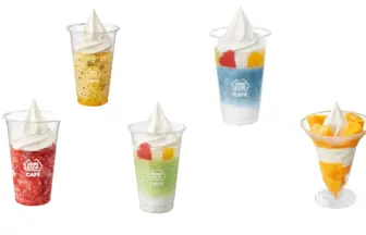 Six clear dessert cups with swirled whipped cream on top, in colors including orange, red, blue, green, and mango, scattered on a white background.