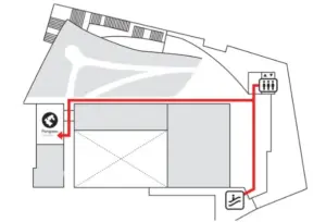 Floor plan with a red accessibility route guiding visitors from the left entrance to the elevator on the right wheelchair icon near bottom