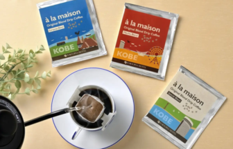 Three à la maison drip coffee sachets from Kobe Hotel arranged around a cup with a pour-over brewing setup.