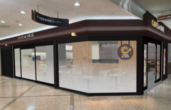 Cafe de CRIÉ storefront in a mall with dark brown framing frosted glass walls and a round logo seating is visible inside