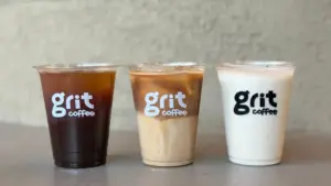Three grit coffee cups lined up on a table iced black coffee iced latte and iced milk drink
