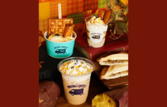 Assorted dessert cups with whipped cream and drizzle, plus a waffle sandwich on a wooden board, autumn-themed backdrop.