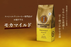 Package of Sarutahiko Coffee Mocha Mild 150g with gold and yellow design logo on front against a warm brown background Japanese branding text on left and vertical slogan on right