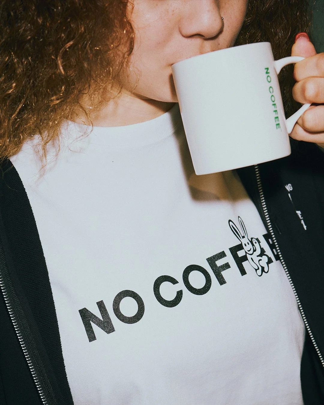NO COFFEEのロゴ入りマグカップで飲み物を飲む女性