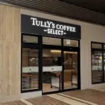 Exterior view of a Tullys Coffee Select storefront with glass doors and large windows along a brick paved walkway