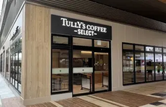 Exterior view of a Tully's Coffee Select storefront with glass doors and large windows along a brick-paved walkway.