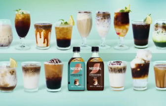 Assorted iced coffee drinks on a mint green shelf with two Nescafe Espresso Base bottles in the center