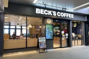 Becks Coffee storefront with large illuminated sign glass windows and customers inside