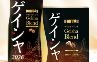 Two Doutor Geisha Blend coffee packaging boxes, one tall black bag and one dark box, featuring Japanese script, 'Geisha Blend', 'Drip Café', 'Roasted in Japan', and '2026' with coffee leaf motifs.