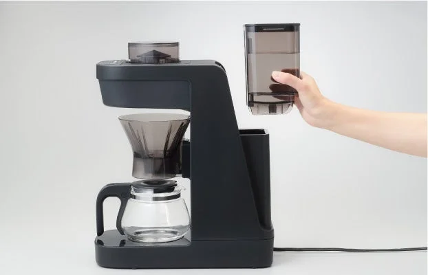 黒いコーヒーメーカーが写っており、水タンクをセットしようとしている手が確認できます