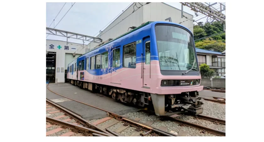 Front and side view of a blue and pink passenger train on tracks beside a station