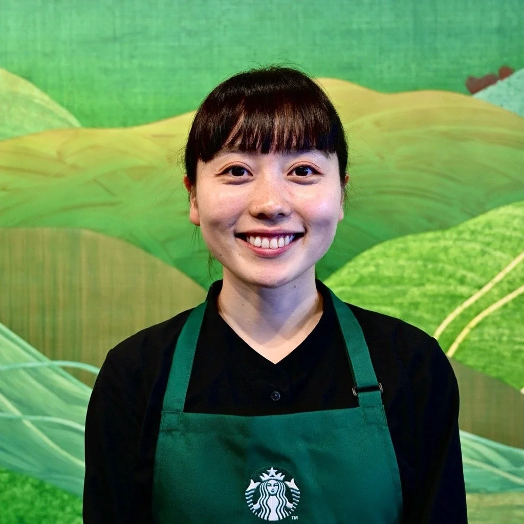 スターバックスのエプロンを着用し笑顔の女性バリスタ