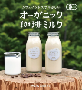 Two bottles of Organic Coffee Milk on a wooden stump with a glass of milk and scattered coffee beans green leafy background
