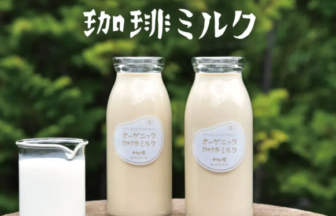 Two bottles of Organic Coffee Milk on a wooden stump with a glass of milk and scattered coffee beans green leafy background