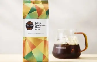 Bag of Tullys Coffee Anniversary Blend 2026 beside a glass carafe of dark brewed coffee on a light table