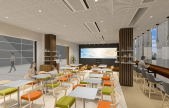 Modern office cafe area with rows of small square tables and colorful chairs wooden pillars and a large screen on a dark back wall at the far end