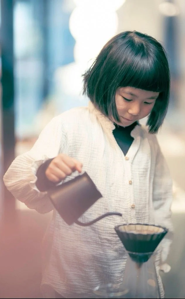 白いシャツを着た少女がハンドドリップコーヒーを淹れている様子