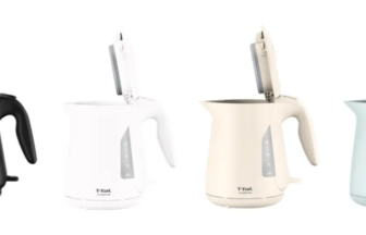 Four electric kettles in black white cream and light blue with lids open arranged in a row T fal