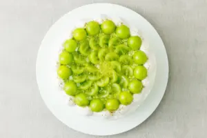 6b50c02686d2aad0f622f35b42d8bc87 | コーヒーステーション Round white cake topped with bright green grapes and curled kiwi green slices on a white plate